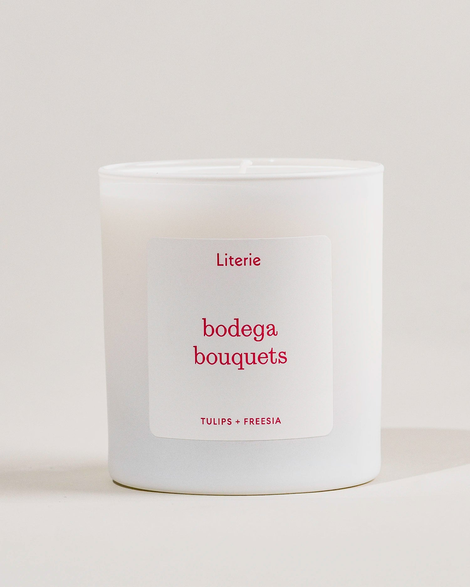 White Literie candle with a label saying 'bodega bouquets'  on a light gray background