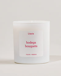 White Literie candle with a label saying 'bodega bouquets'  on a light gray background