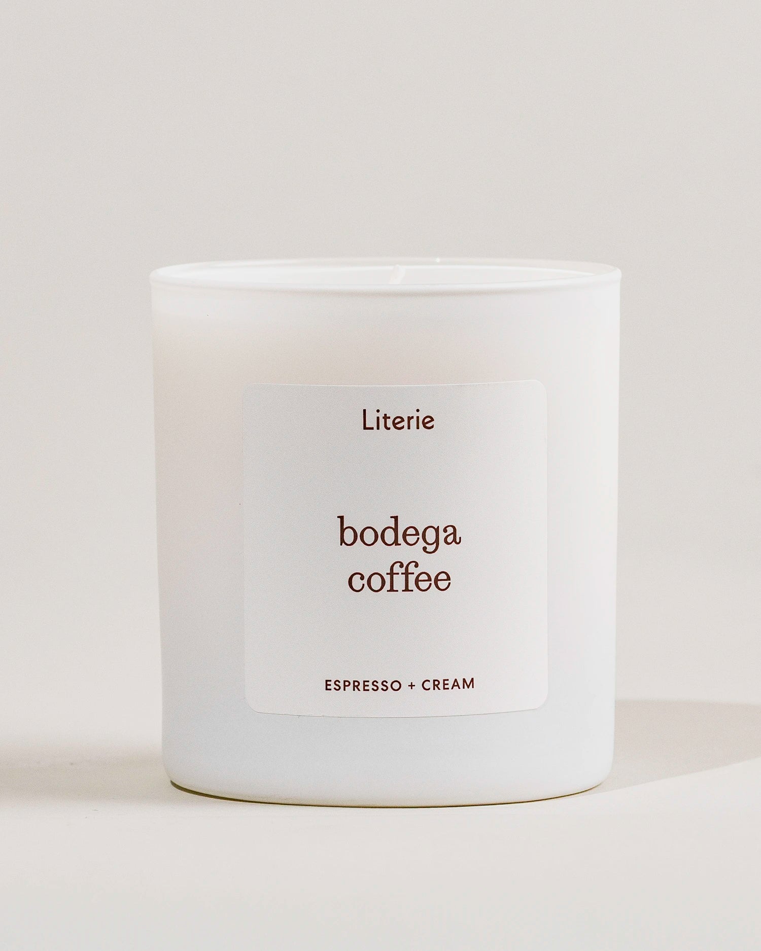 White candle with 'bodega coffee' label from Literie on a light gray background