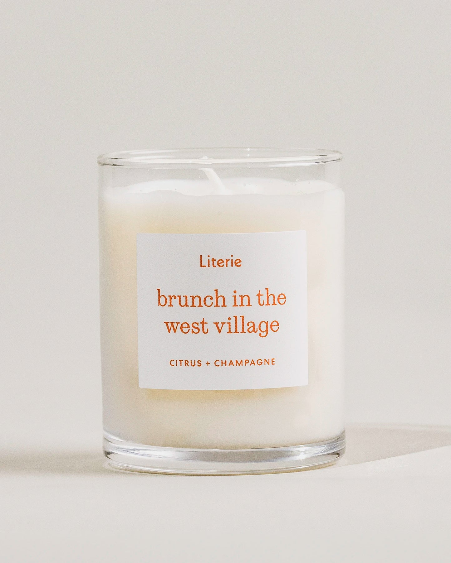Little candle with a label reading 'brunch in the west village' on a light background
