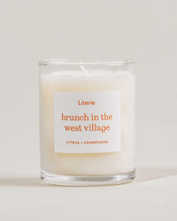 Little candle with a label reading 'brunch in the west village' on a light background