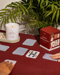 People playing canasta on a table with a candle and candle box.