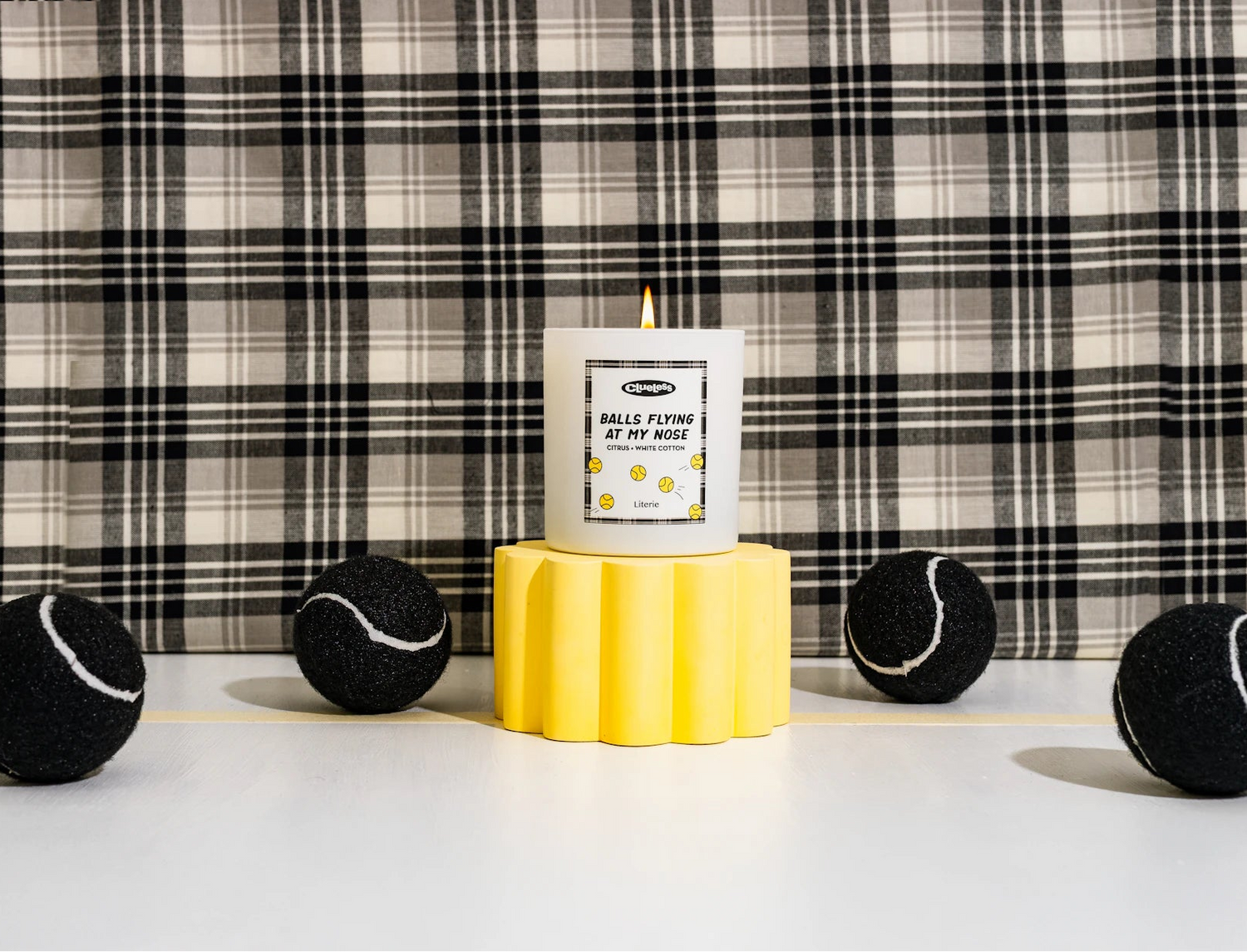 Clueless candle with tennis balls on a checkered background.