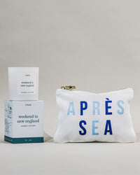 White pouch with 'Après Sea' text,  'weekend in new england' candle and candle box on a light gray background