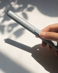 Hand holding a silver lighter with a blurred background