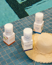 European inspired candle set and a straw hat on a tiled poolside surface