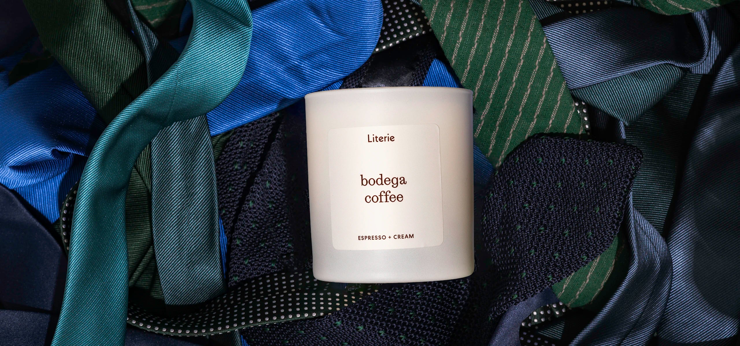 Literie candle labeled 'bodega coffee' on a pile of ties.