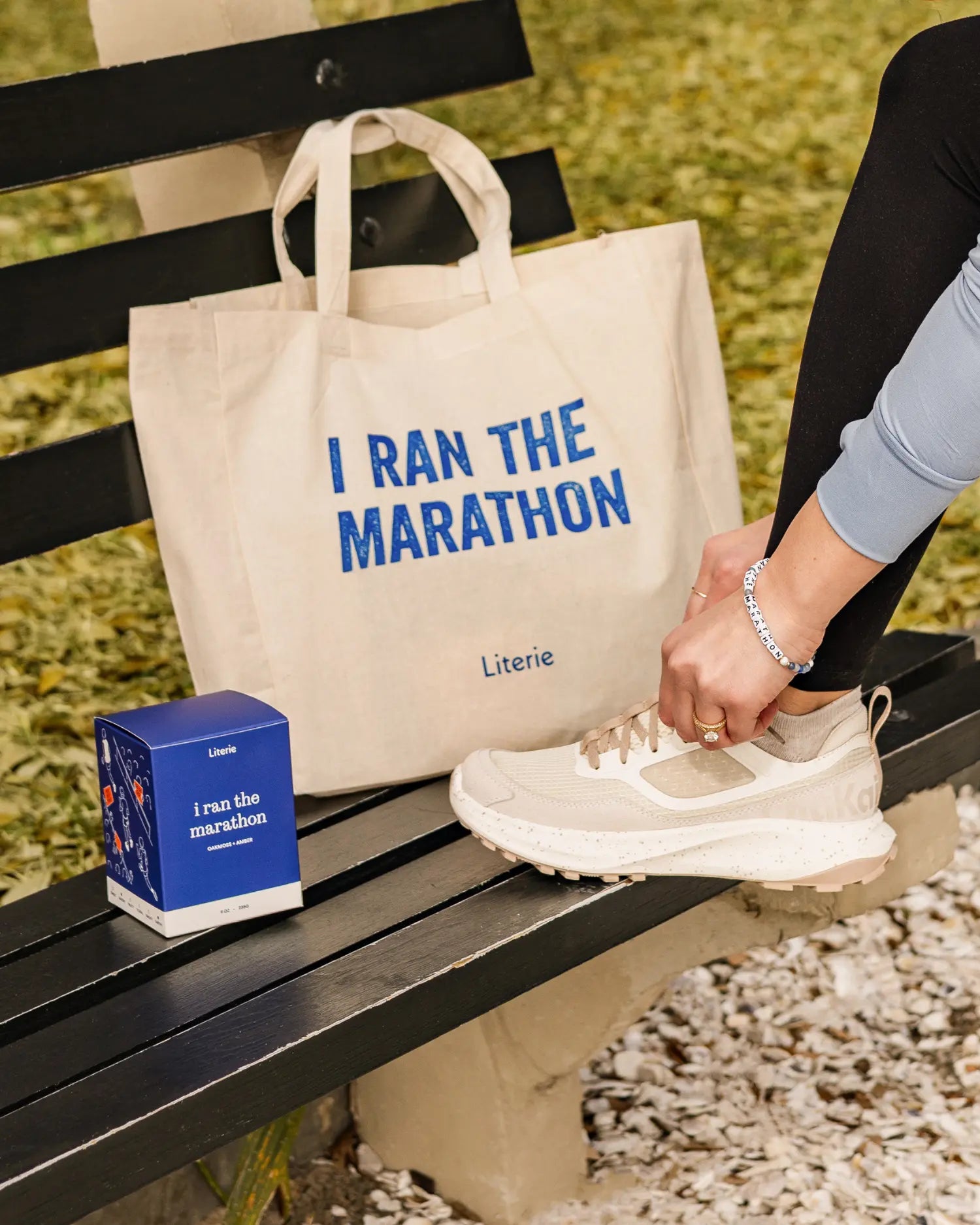 I ran the marathon tote and candle sitting on bench with person tying shoe and wear Little Words Project bracelet.