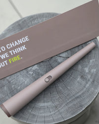 Pink lighter on a wooden surface with a motivational quote on a card.