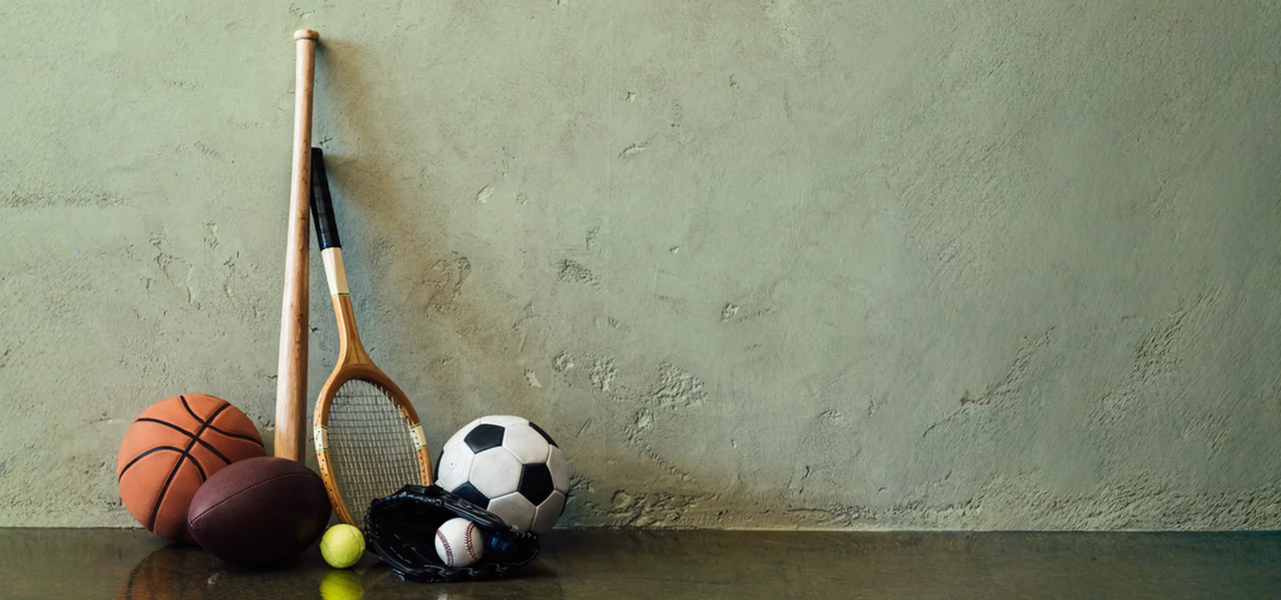 Various sporting equipment against a green wall.