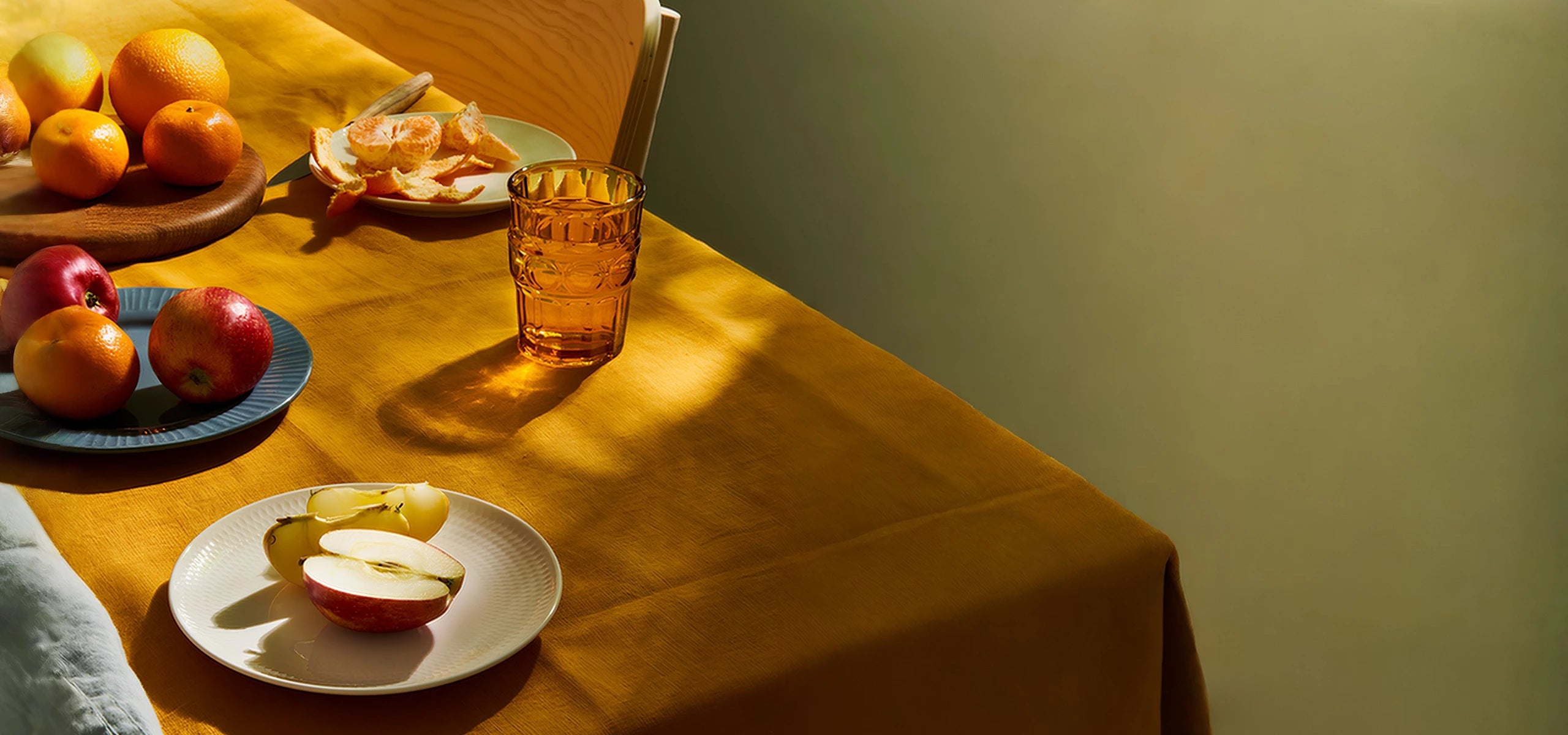 Various food on an orange tablecloth against a green wall.