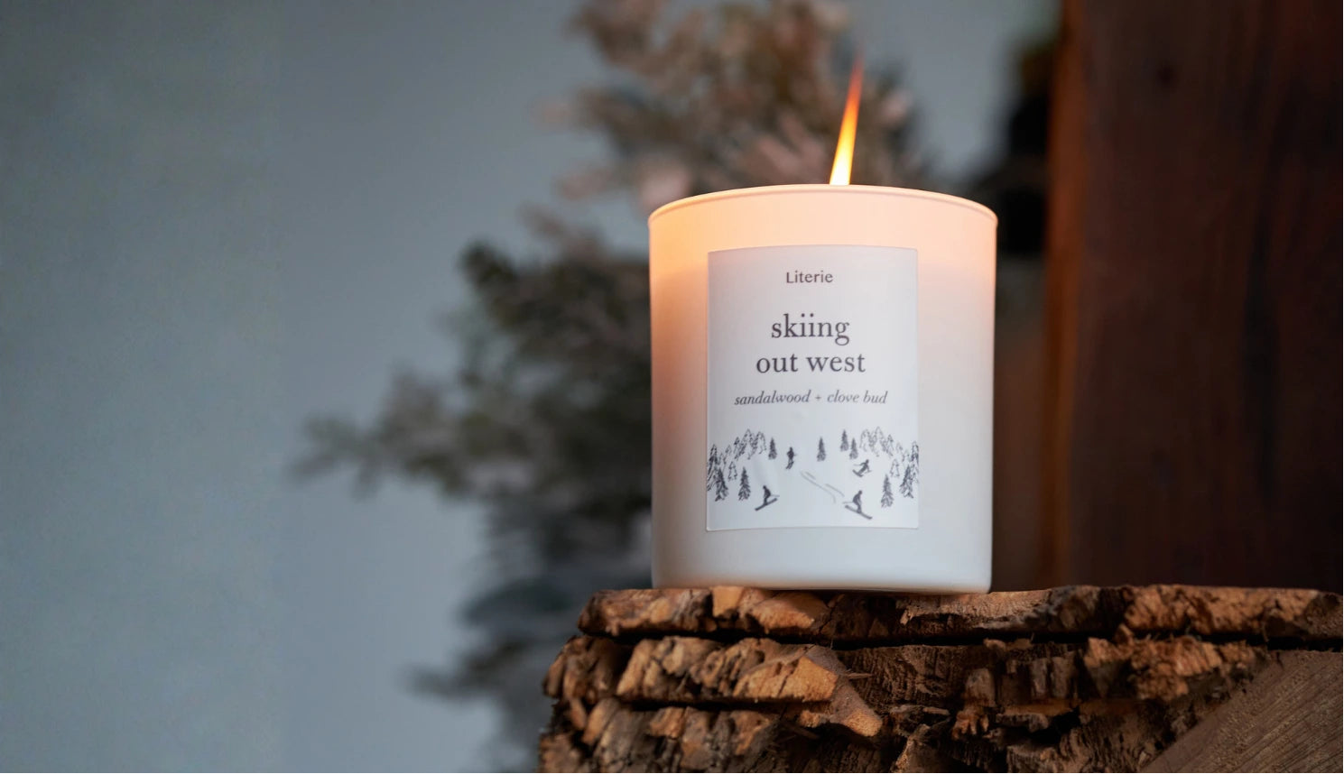 Candle with a label on a wooden surface against a blurred background