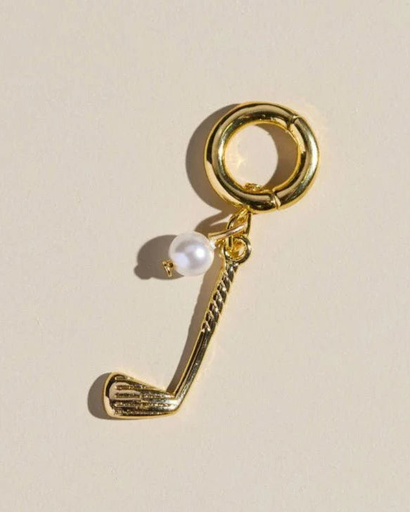 Gold charm with a pearl on a beige background