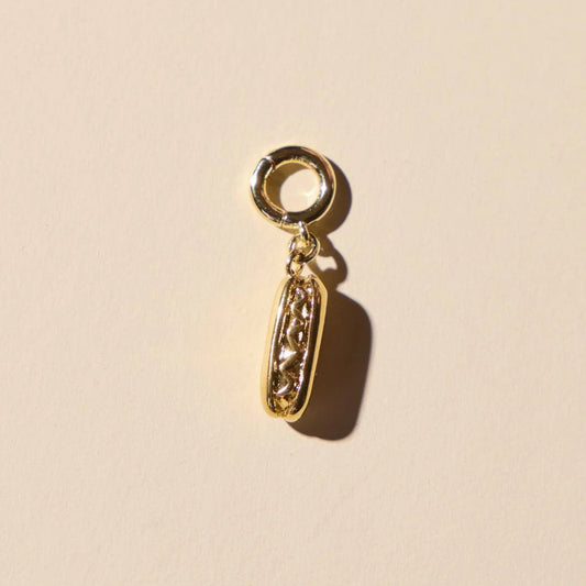 Hotdog 14 karat gold plated charm for jewelry in tan background.