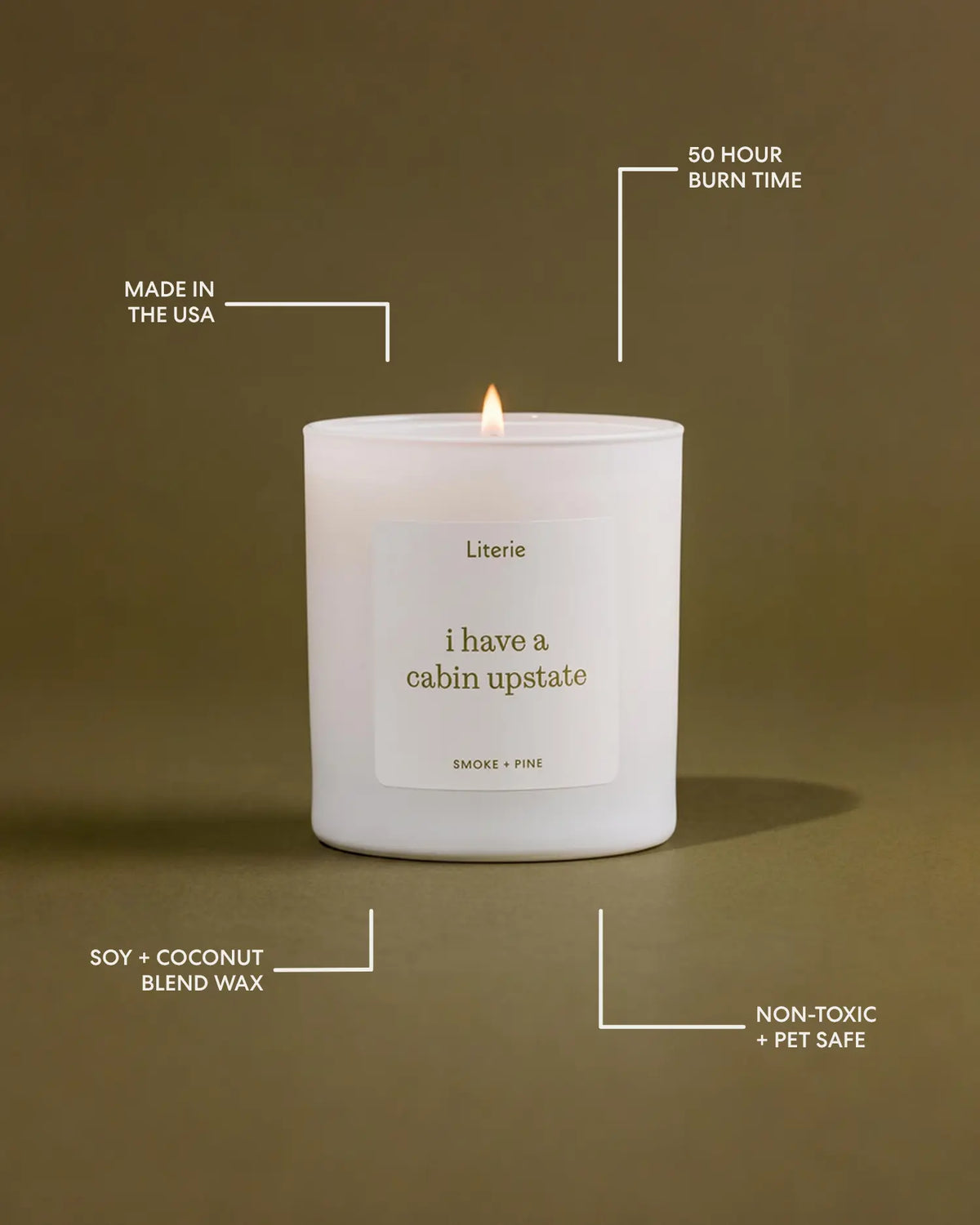 A white candle labeled 'i have a cabin upstate' by Literie, lit with a small flame, centered on a warm brown background with white callout text highlighting product features.