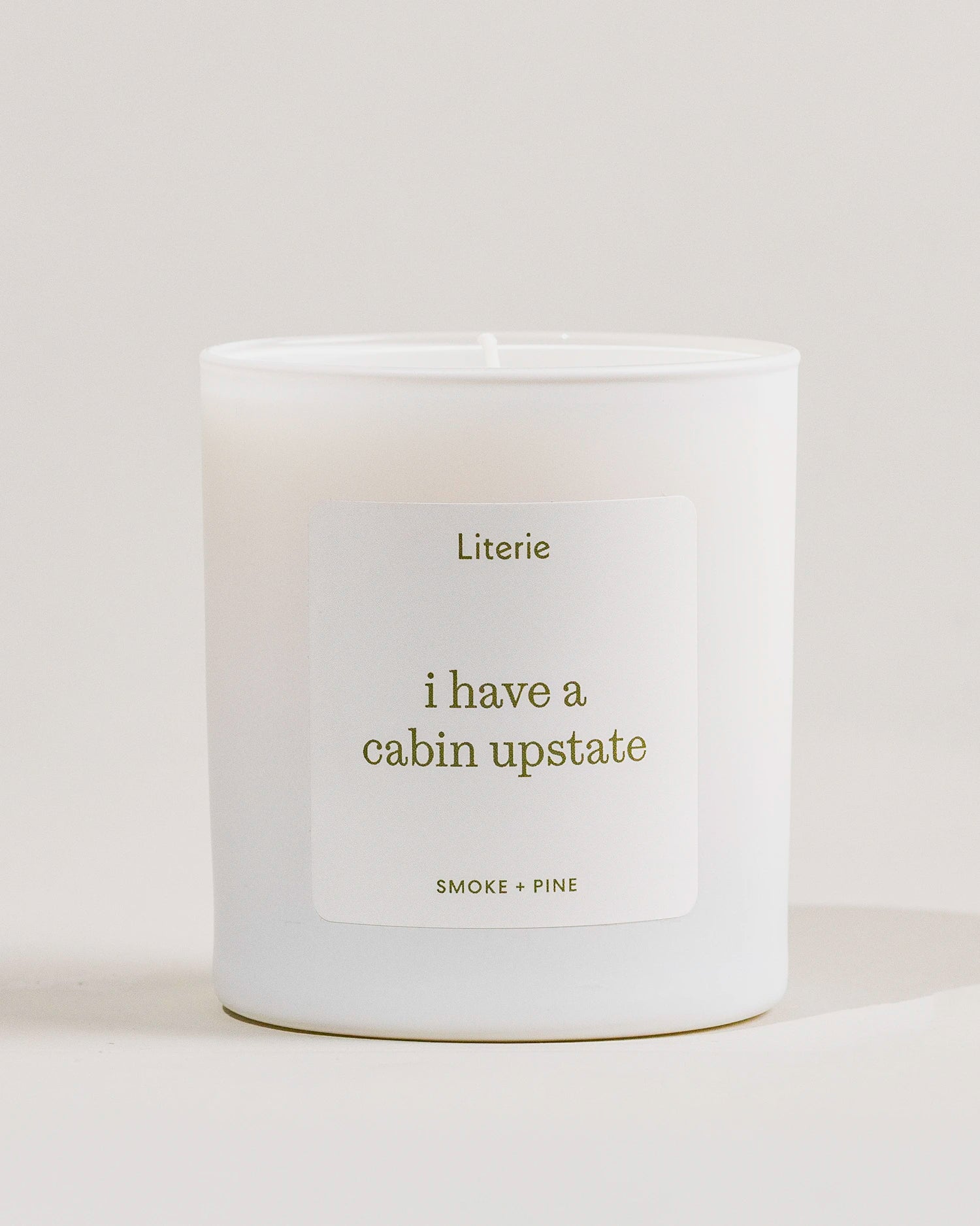 White 'i have a cabin upstate'c andle with a label on a light gray background