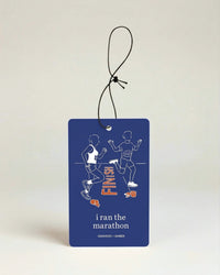 Blue air freshener with running design and 'i ran the marathon' text on a beige background