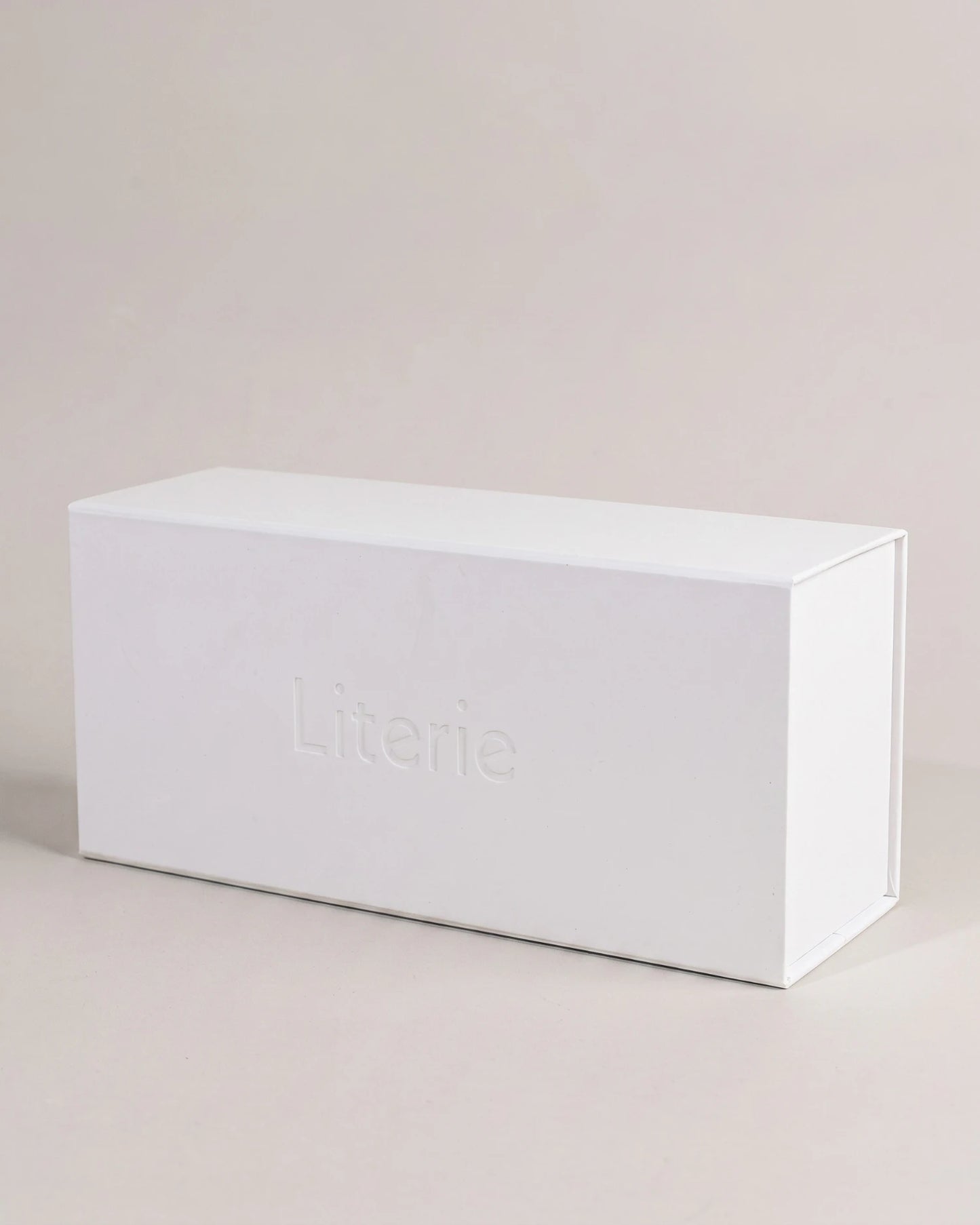 A minimalist white rectangular candle box with the brand name 'Literie' embossed on the front, set against a solid light beige background.