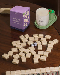 Mahjong game pieces with a purple candle box and candle on a green tray with green matches