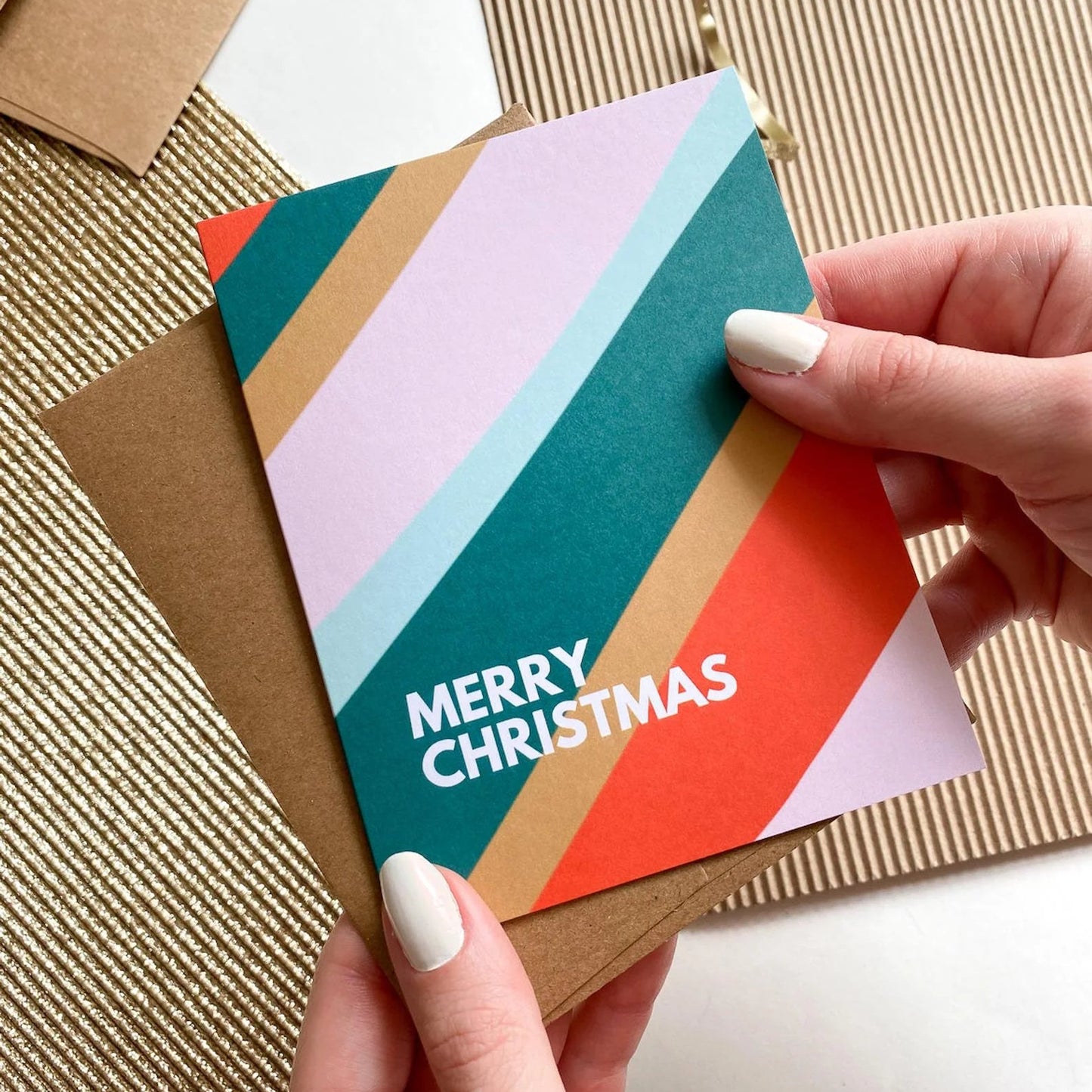 Colorful 'Merry Christmas' card held by a hand on a textured surface