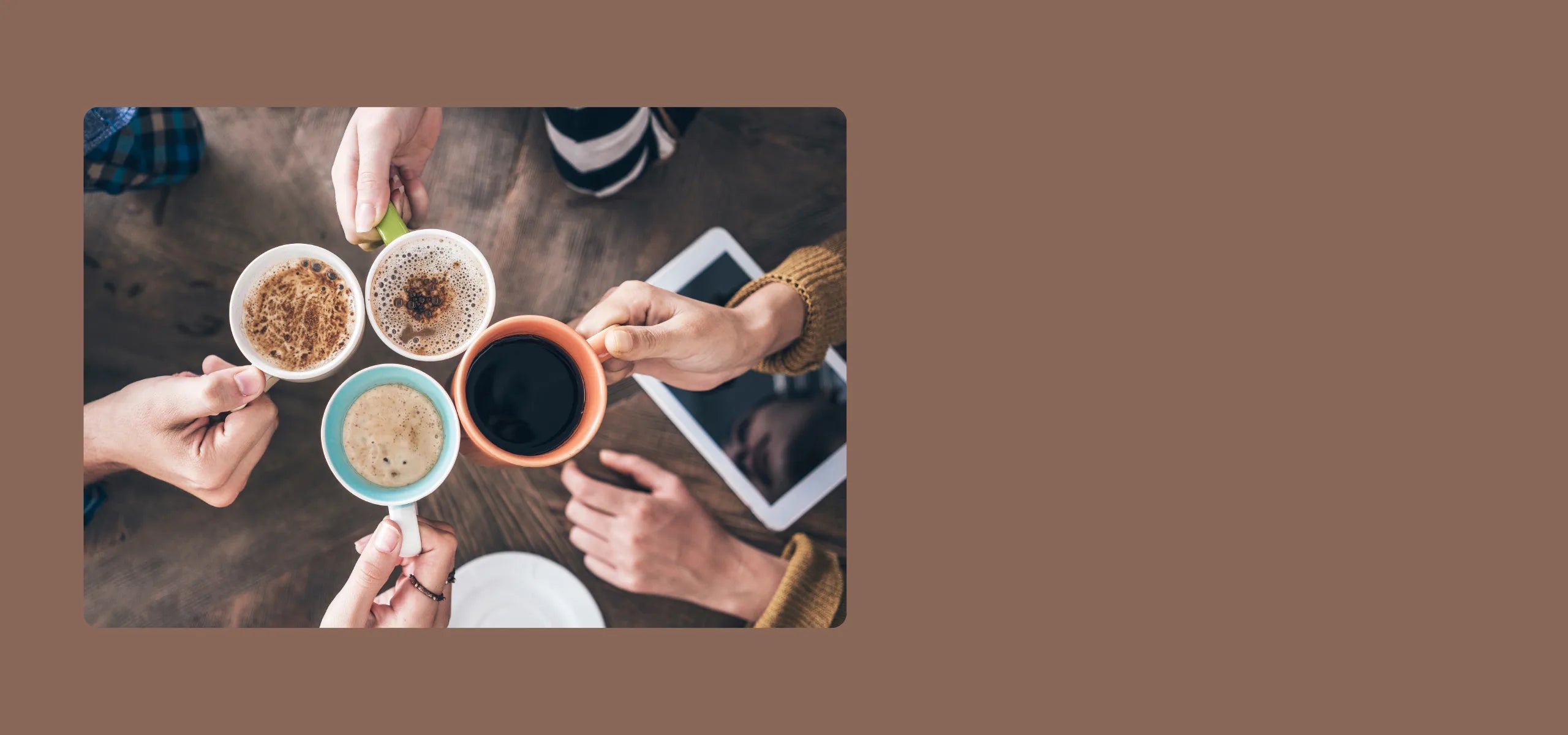 People holding cups of coffee and different types of coffee on a wooden table.