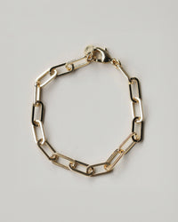 Gold chain bracelet on a light gray background
