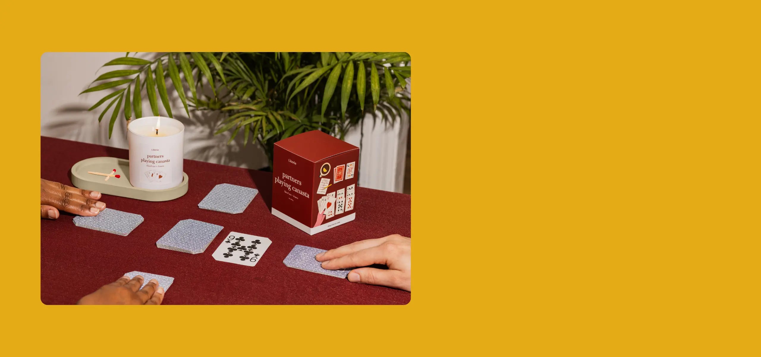 Card game setup with cards and a candle and box on a table, yellow background