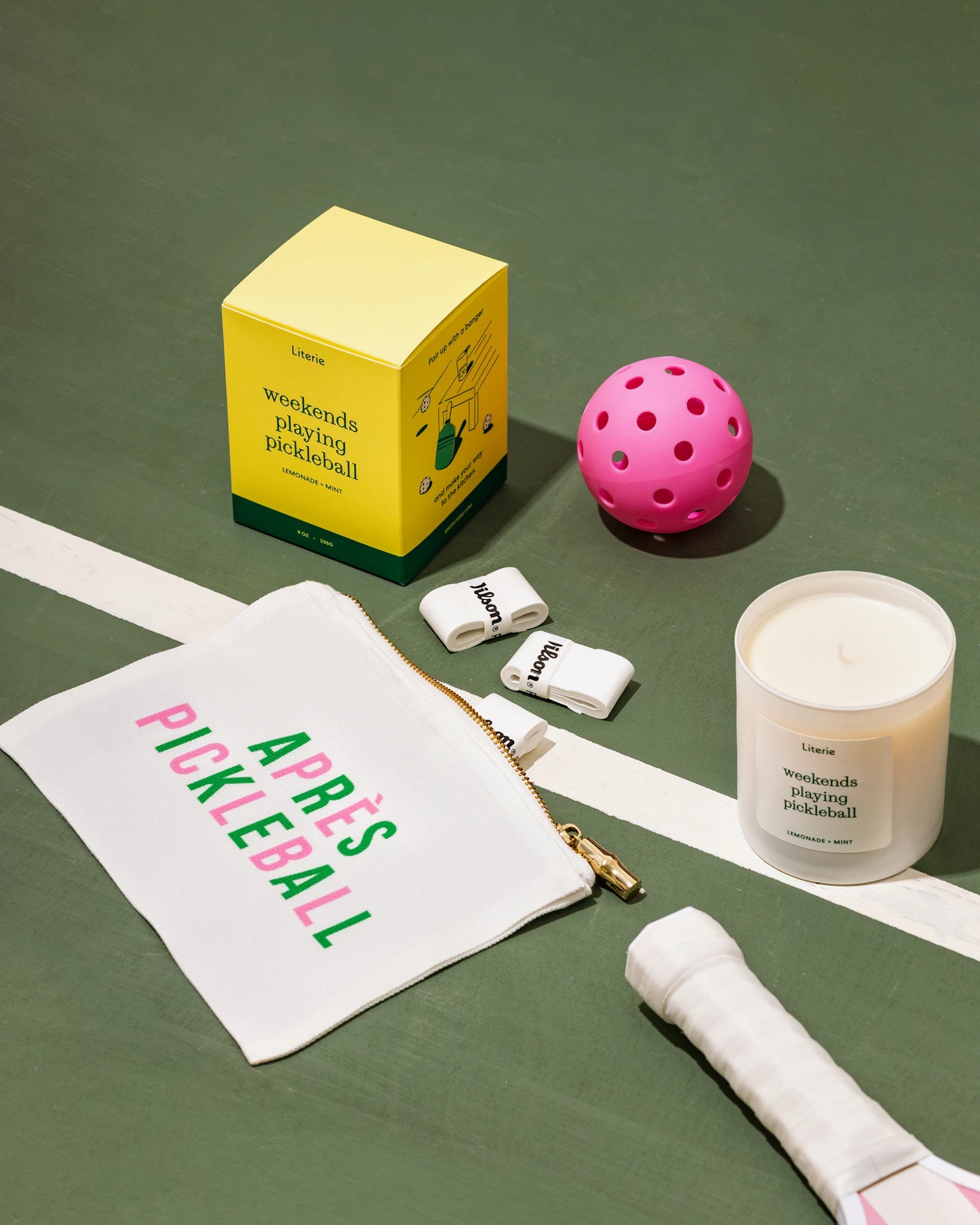 'weekends playing pickleball' candle with pouch and pickleballs on court.