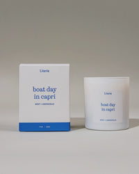 Candle and packaging of 'boat day in capri' spinning on light gray background
