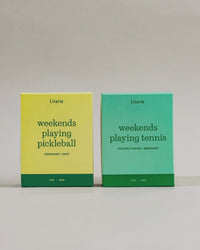 'weekends playing pickleball' and 'weekends playing tennis' candles boxes on a neutral background turning 360.