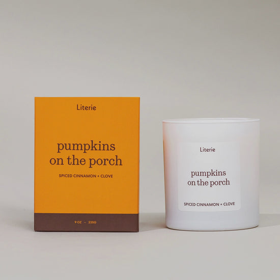 Literie "pumpkins on the porch" candle box spinning in a circle to show off hand drawn artwork next to candle on a grey background.