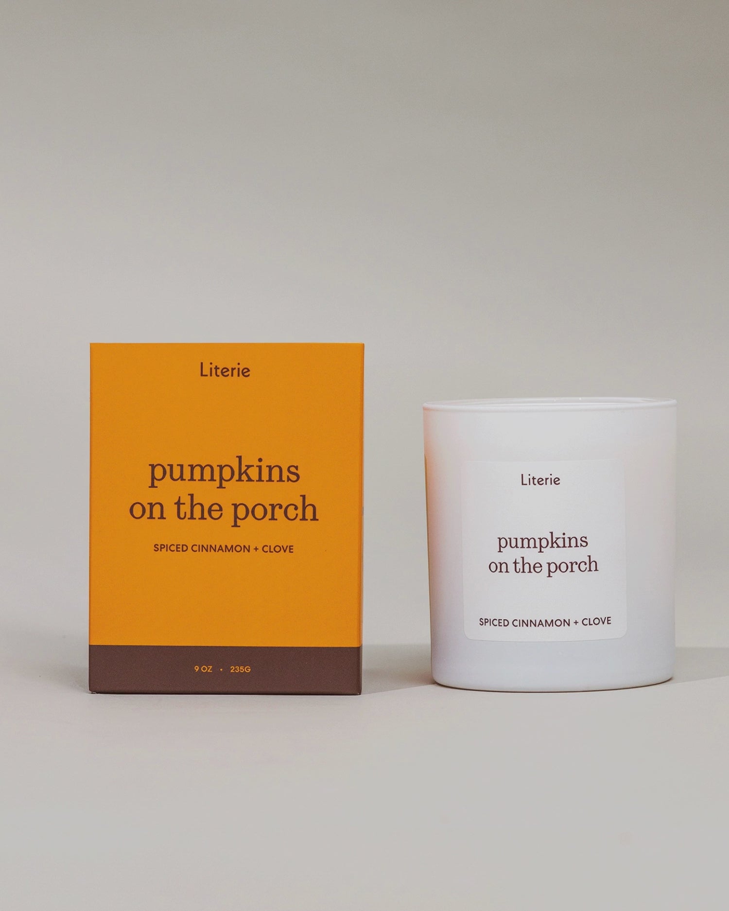 Literie "pumpkins on the porch" candle box spinning in a circle to show off hand drawn artwork next to candle on a grey background.