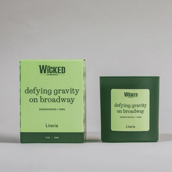Wicked on Broadway candle named 'defying gravity on broadway' next to packaging spinning.