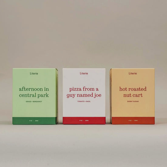 Literie's "I Love NY" candle trio spinning to show of product packaging illustrations on a grey background. 