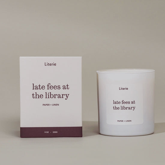"late fees at the library"candle next to it's box that's rotating to view illustrations on the box. 