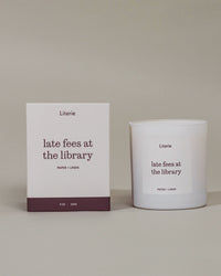 "late fees at the library"candle next to it's box that's rotating to view illustrations on the box. 