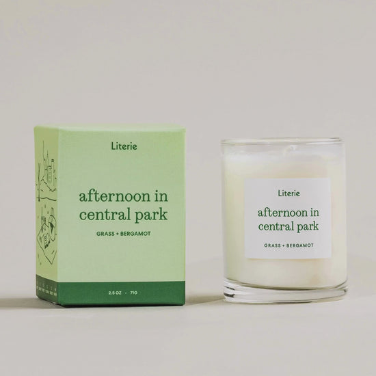 "afternoon in central park" little candle box spinning with the candle next to it on a light grey background.