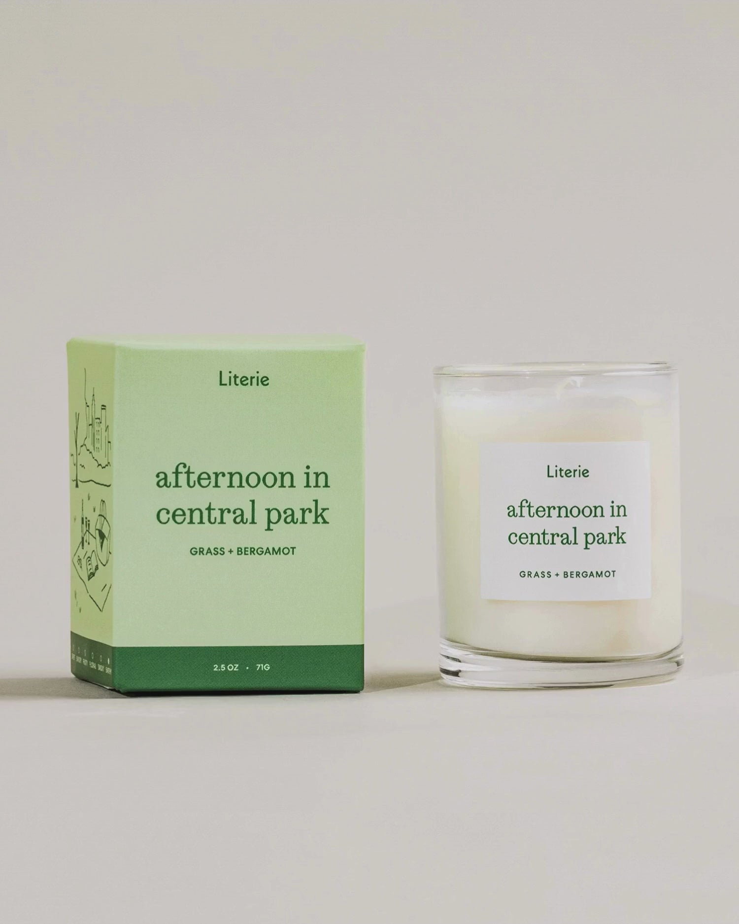 "afternoon in central park" little candle box spinning with the candle next to it on a light grey background.