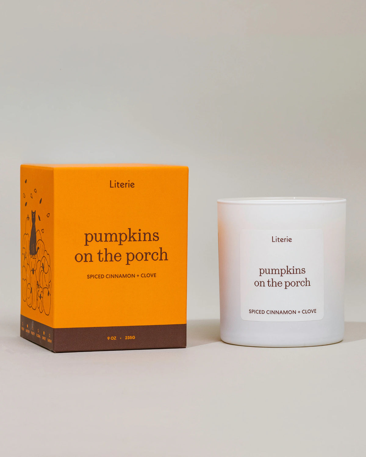 A Literie 'pumpkins on the porch' scented candle shown next to its bright orange packaging box on a neutral light gray background.