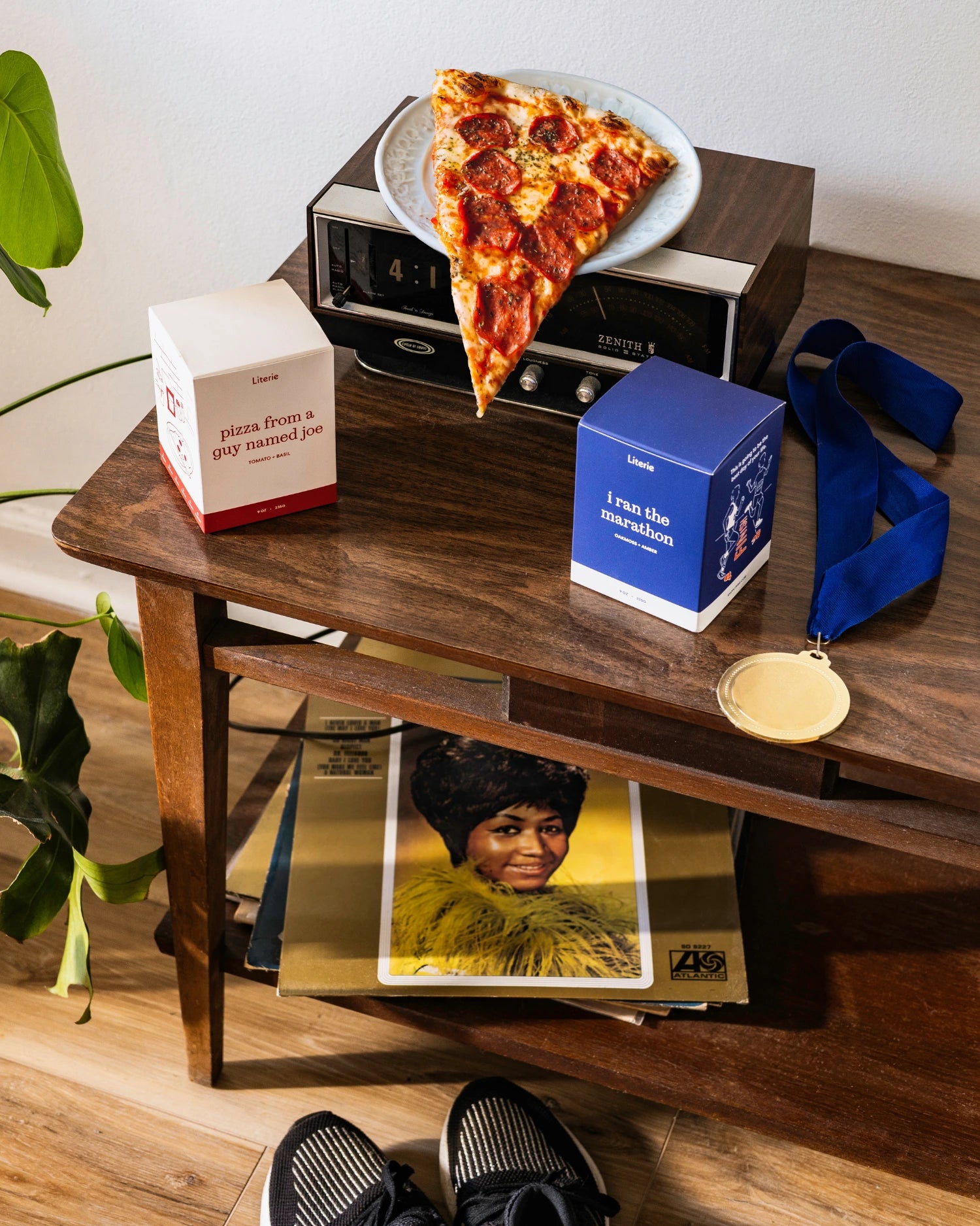 'i ran the marathon' and 'pizza from a guy named joe' candles on a table with a medal and slice of pizza.