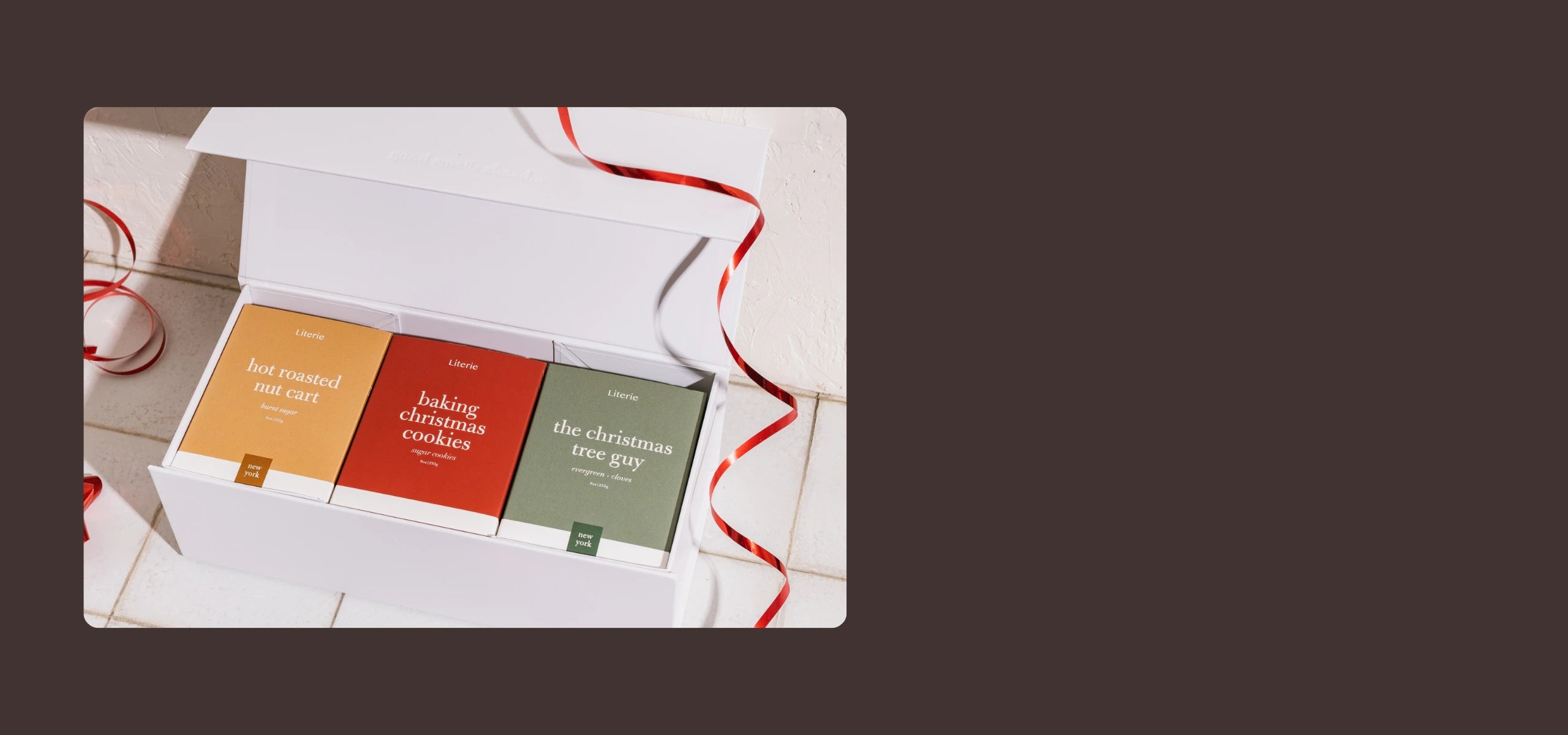 Set of candles in boxes with a red ribbon on a white surface.