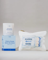 'I have a house down the shore' candle, box, and pouch with 'Seaside Shore' text on a gray background.