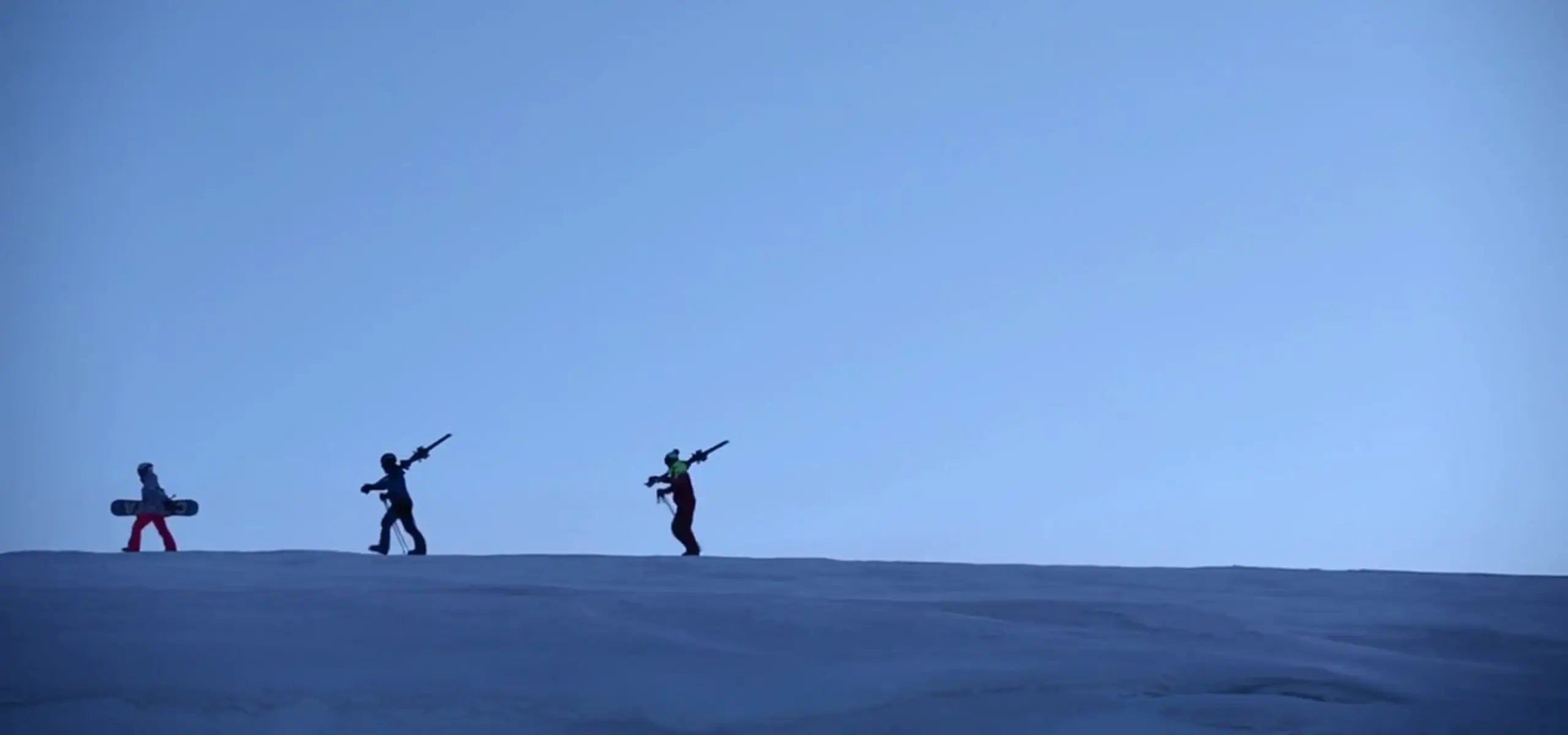 3 people hiking up a mountain to ski