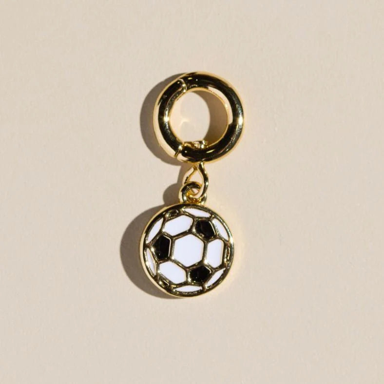 Gold charm with a soccer ball design on a beige background