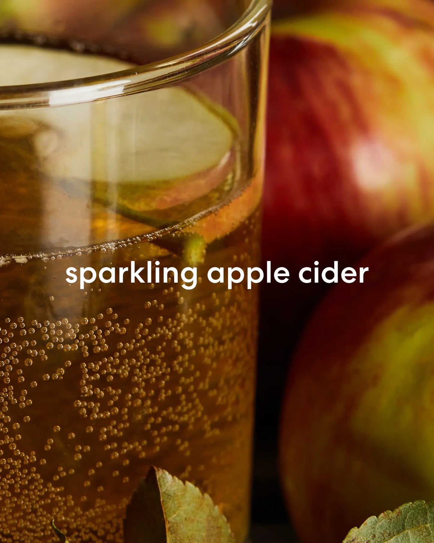 Fresh and sweet smelling sparkling apple cider next to apples.