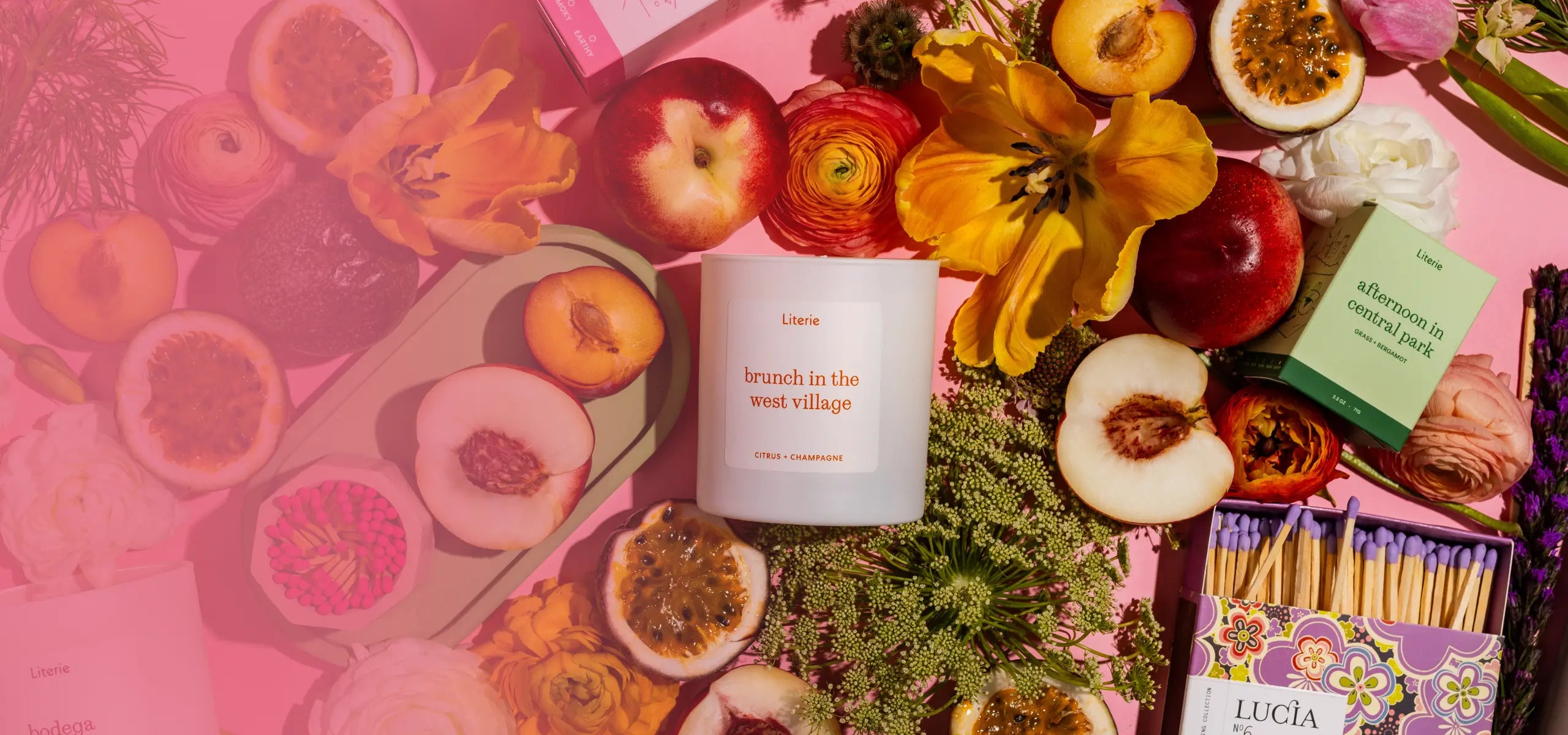 Candle with flowers and fruits on a pink background
