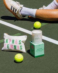 Tennis-themed candle and pouch with tennis balls on a tennis court.