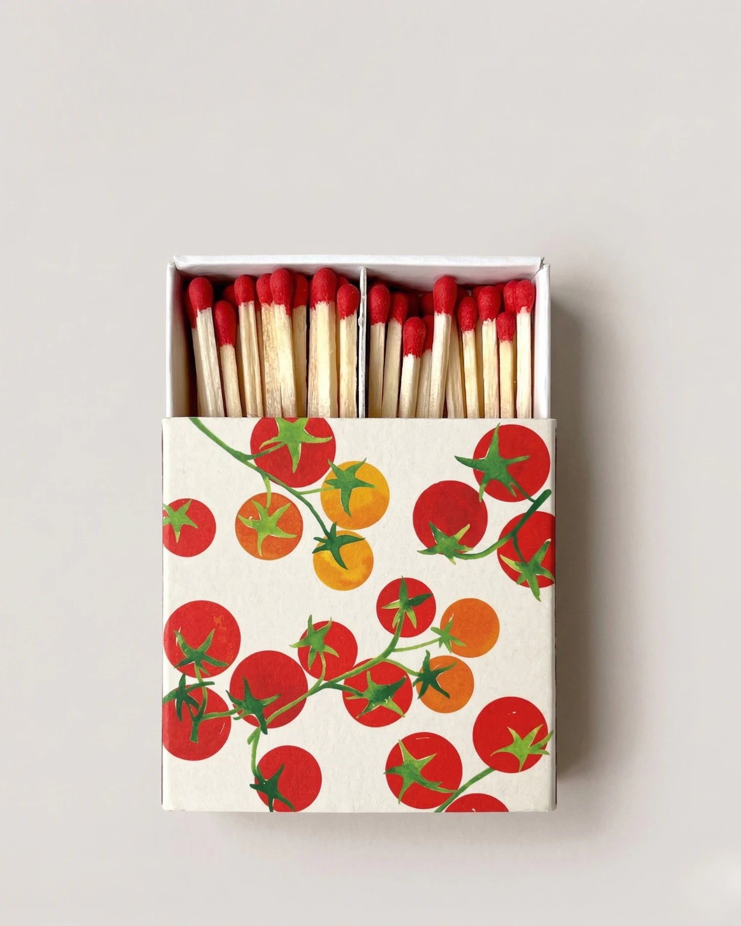 Matchbox with tomato design on a light gray background