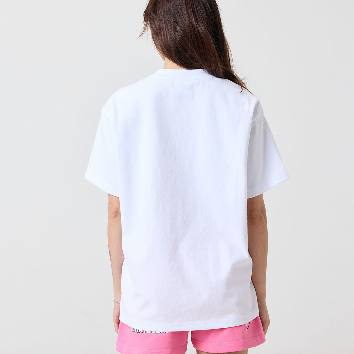Person wearing a white t-shirt and pink shorts on a plain background