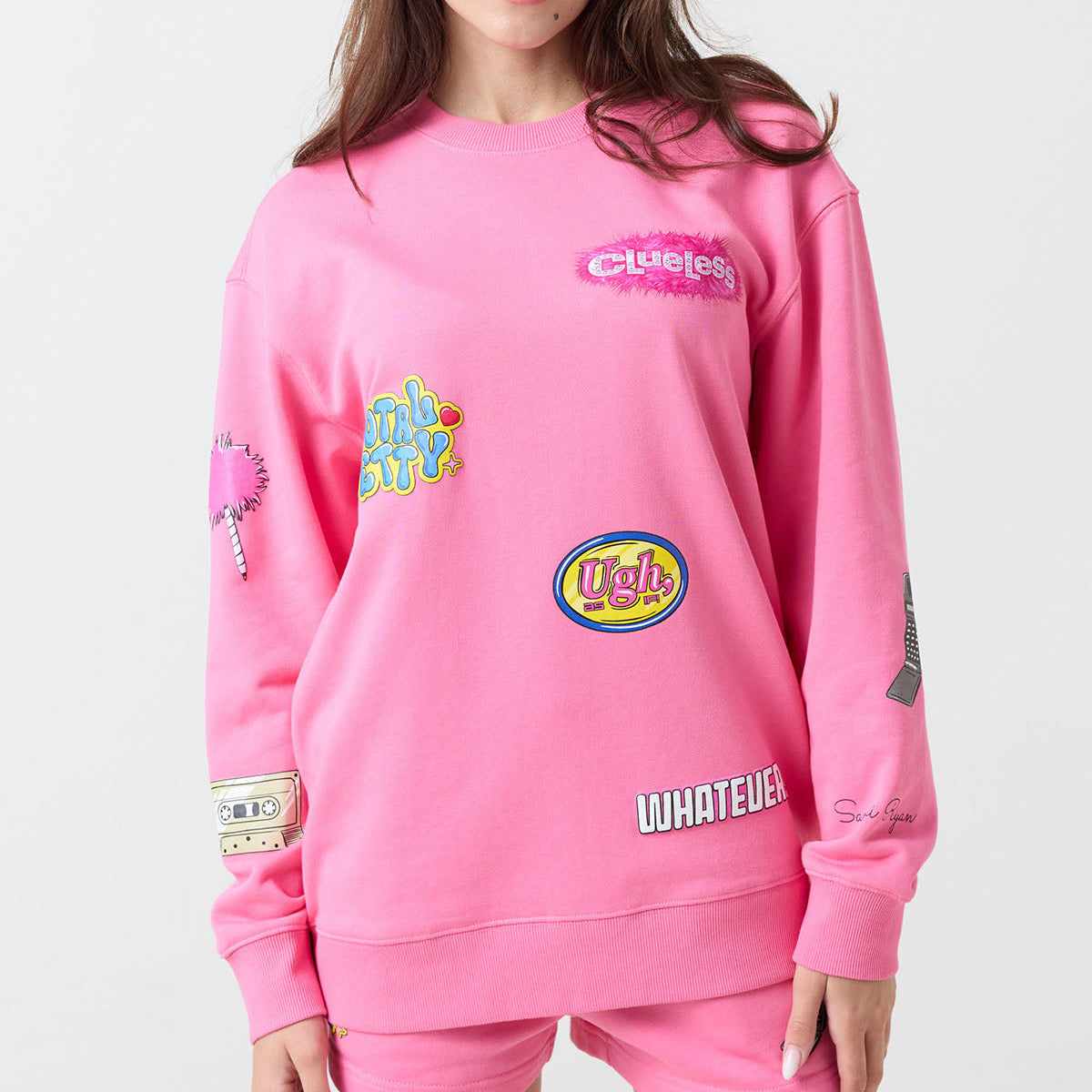Person wearing a pink sweatshirt with various graphics and text on a white background